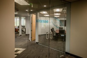 Glass entrance doors with Vitesse signage inside an office